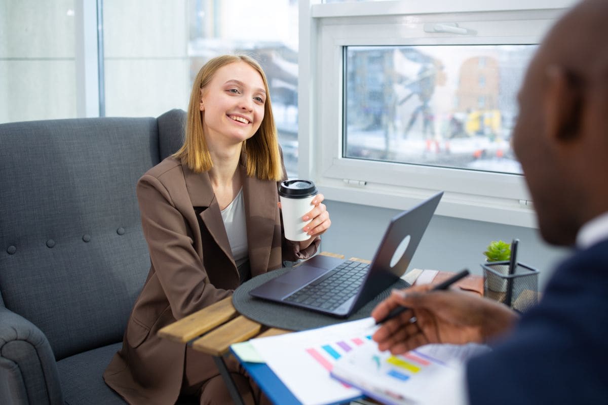 Dois profissionais sorrindo em reunião de negócios com café
